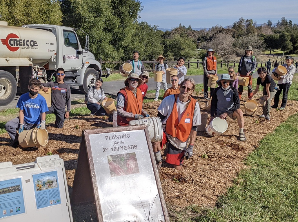 Water truck with planting volunteers in the field