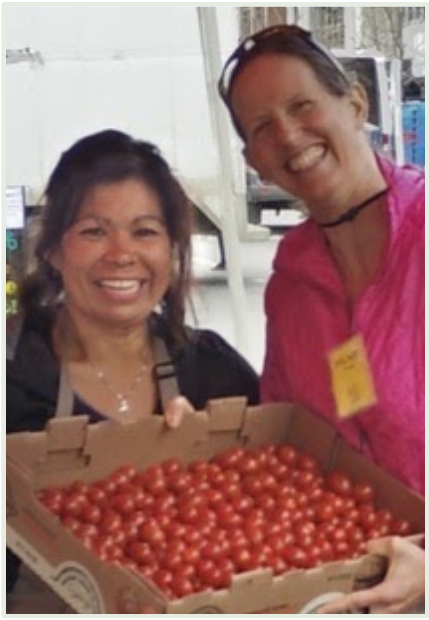 Hilary receives a box of donated tomatoes from a Farmers' Market vendor